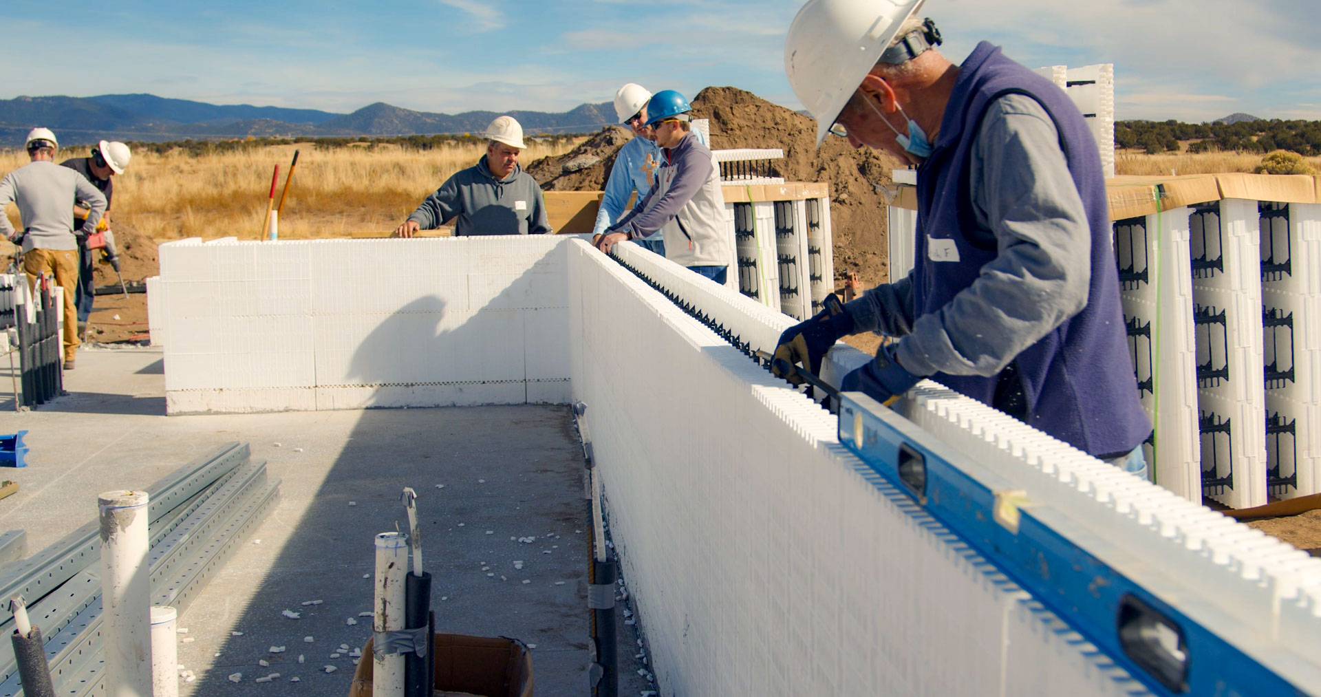 Volunteer placing horizontal rebar into ICF forms.