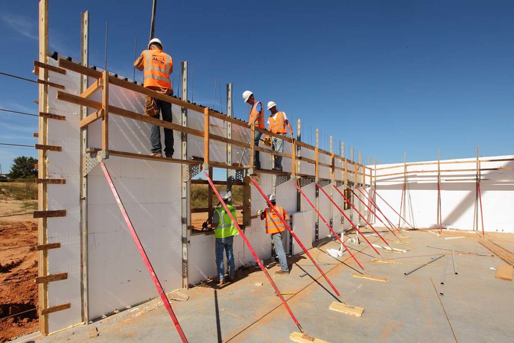 Crew members pour and consolidate concrete from on top of the bracing system